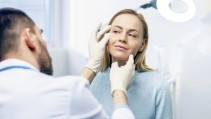 A dermatologist examines the skin around a patient's eye.